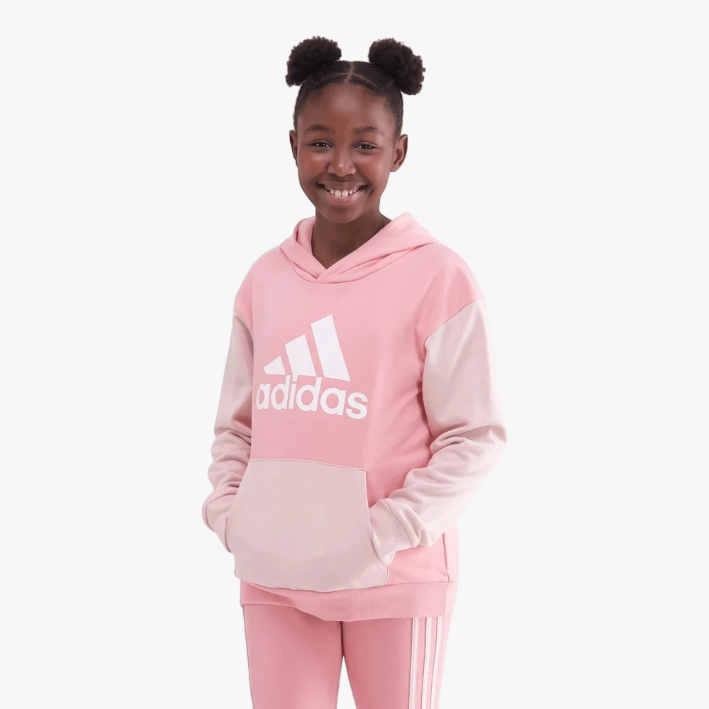 Young girl smiling, wearing an Adidas Girls Cb Hoody in pink with color-block design and matching track pants.