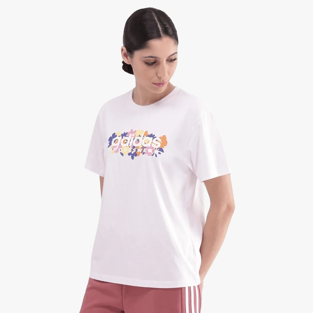 Adidas Womens Soft Short Sleeve Tee in white, featuring a colorful floral Adidas graphic. Worn by a woman.