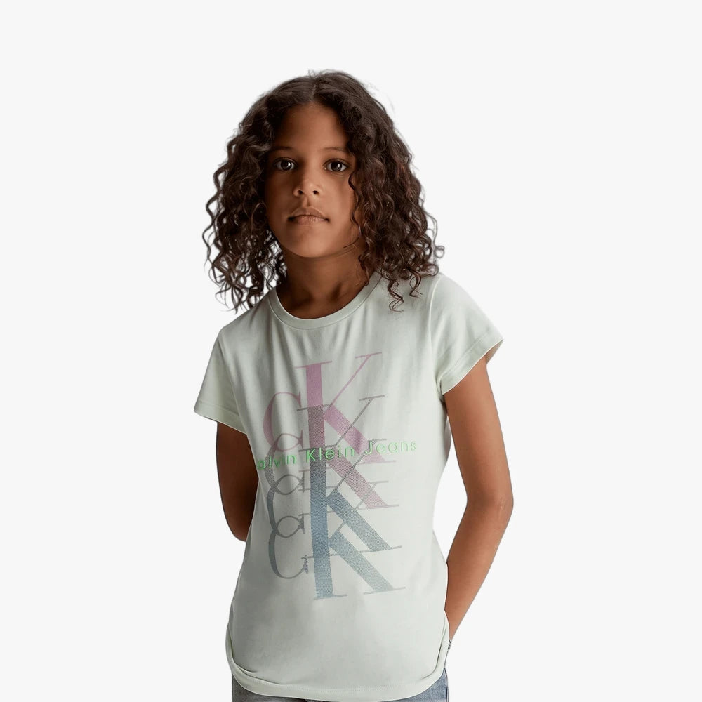 Young girl wearing a light green Calvin Klein Girls Monogram Repeat Tee with multicolor CK logo, short sleeves, and round