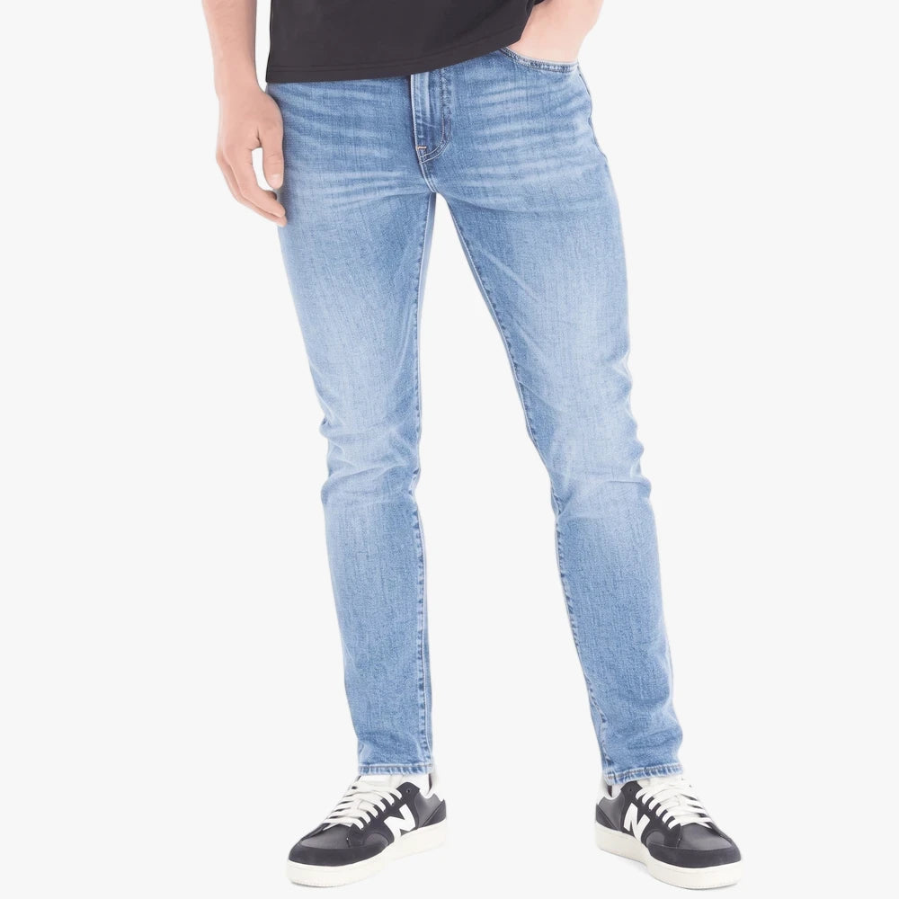 Levis Mens 510 Skinny Jeans Super Worn Advanced. A man stands wearing light wash blue skinny jeans and black and white