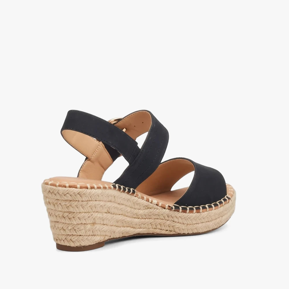 Miss Black Womens Jayda 9 black wedge sandal with espadrille sole, black fabric straps, and gold-tone buckle.