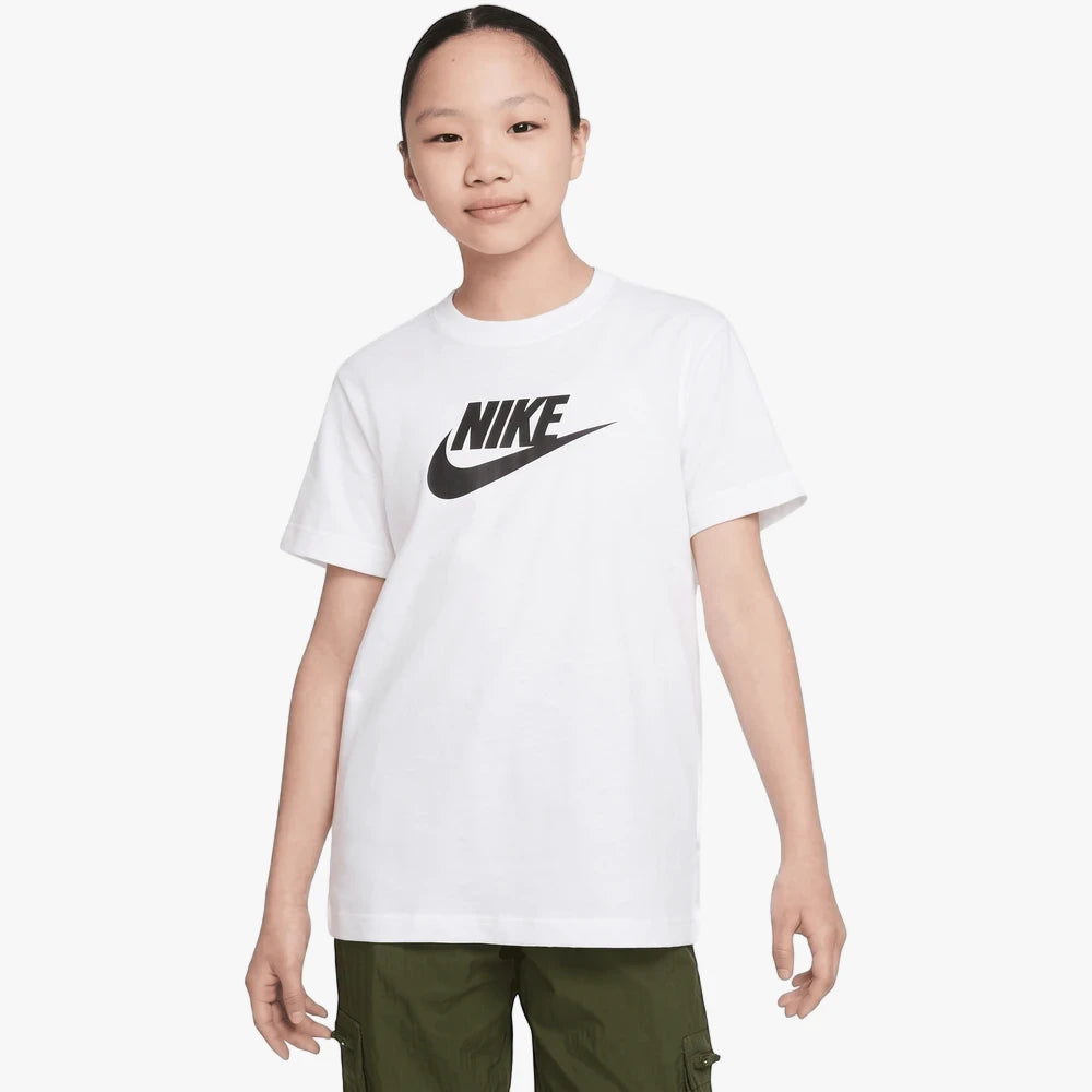 Young girl wearing a white Nike Futura short sleeve tee with a black Nike logo on the chest, paired with green cargo pants.