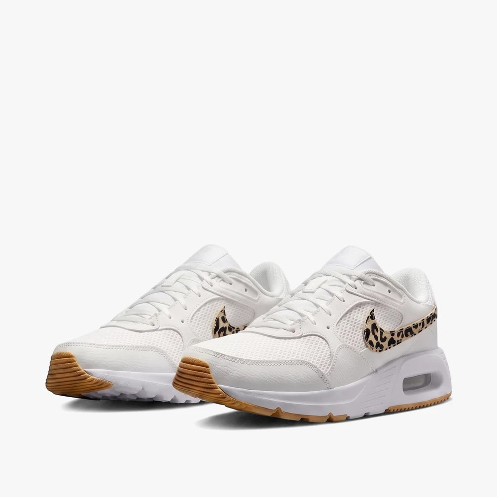 White Nike Womens Air Max SC sneakers with leopard print swooshes and gum rubber soles, angled view.