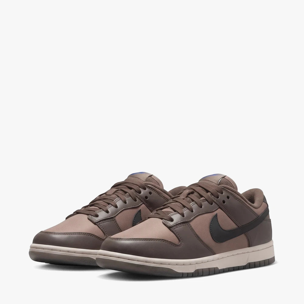 A pair of Nike Womens Dunk Low sneakers in ironstone and anthracite brown, presented in a side view on a white background.