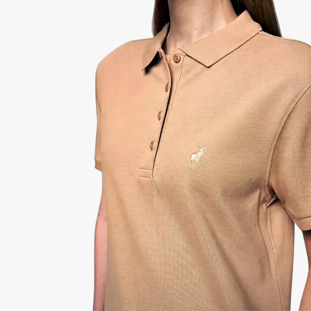 Close-up of a woman wearing a taupe Margot short-sleeve polo shirt, featuring a textured knit fabric and embroidered