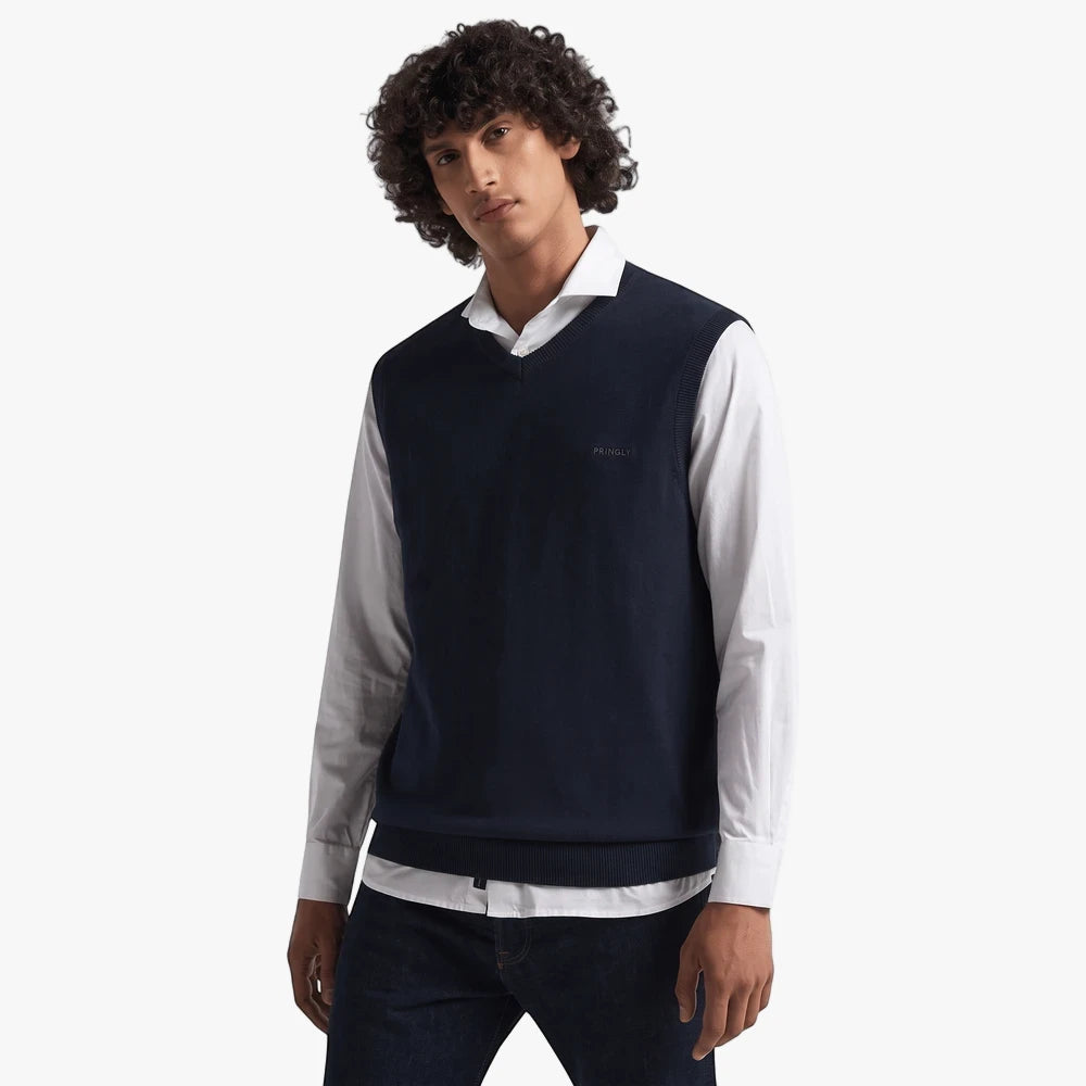 Pringle Mens Ryan Sleeveless Jersey Navy worn by a model, featuring a V-neck and ribbed hem, layered over a white shirt.
