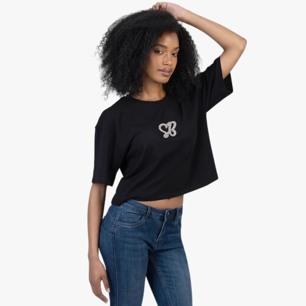 Young woman wearing a black Sissy Boy Endless Spring Boxy Tee with a glitter heart butterfly logo and blue jeans.