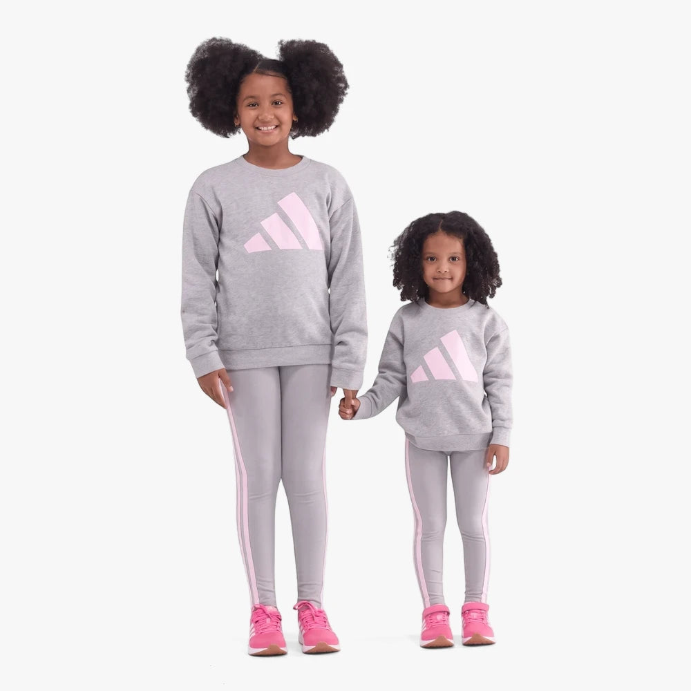Two girls wearing matching grey Adidas Bl Ft sweaters with pink logos, grey leggings with pink stripes, and pink sneakers.