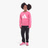 Full-body shot of a young girl wearing a pink Adidas sweatshirt and black Adidas track pants with pink sneakers.