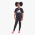 Adidas Girls Black Leggings and black t-shirt set, modeled by a young girl wearing pink sneakers, full body view.