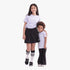 Two girls wearing matching Adidas Girls Varsity Short Sleeve Tee in violet, black skirts/pants, and sneakers, smiling in a