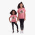 Two girls in pink Adidas Kids Floral Short Sleeve Tees with a colorful trefoil logo, black striped leggings, and sneakers.