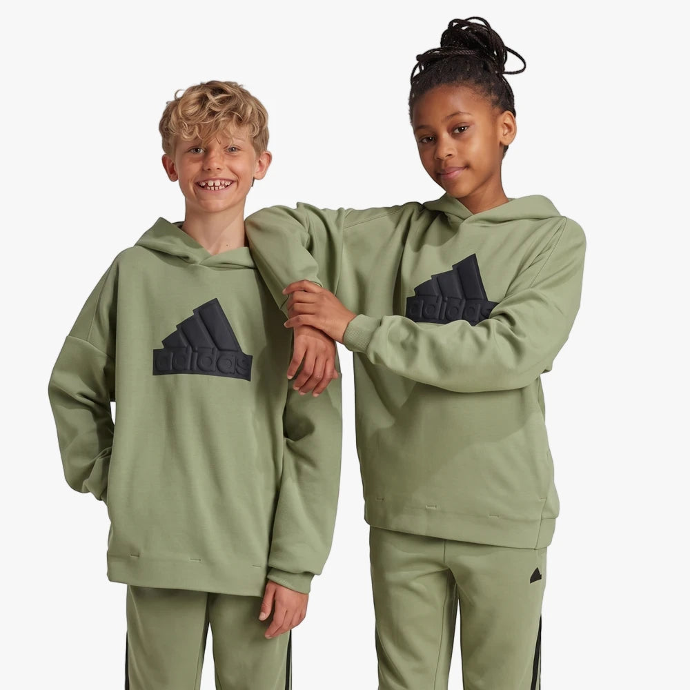 Two children wearing matching olive green Adidas Future Icons Logo Hoodies with black logos and track pants.