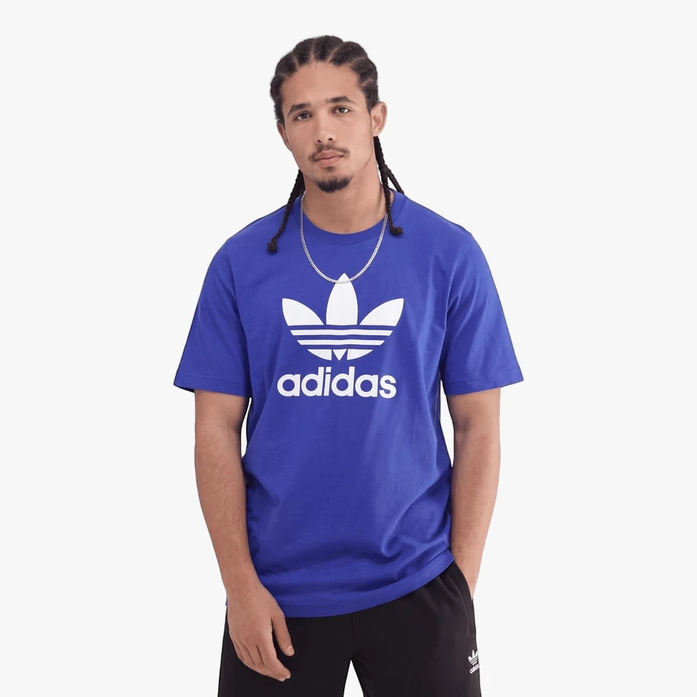 Adidas Mens Trefoil Adicolor Short Sleeve Tee in Semi Lucid Blue worn by a model, featuring the white Trefoil logo, paired