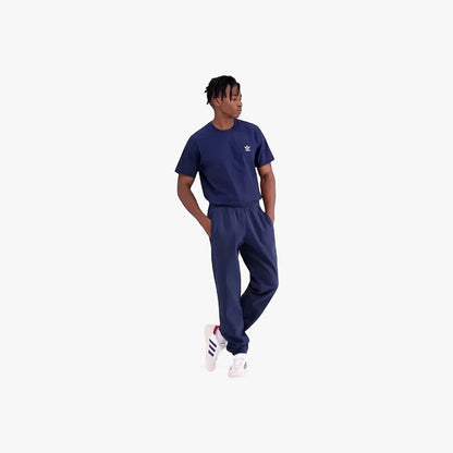 Male model wearing navy blue Adidas Mens Trefoil Essentials French Terry Joggers and matching t-shirt with white sneakers.