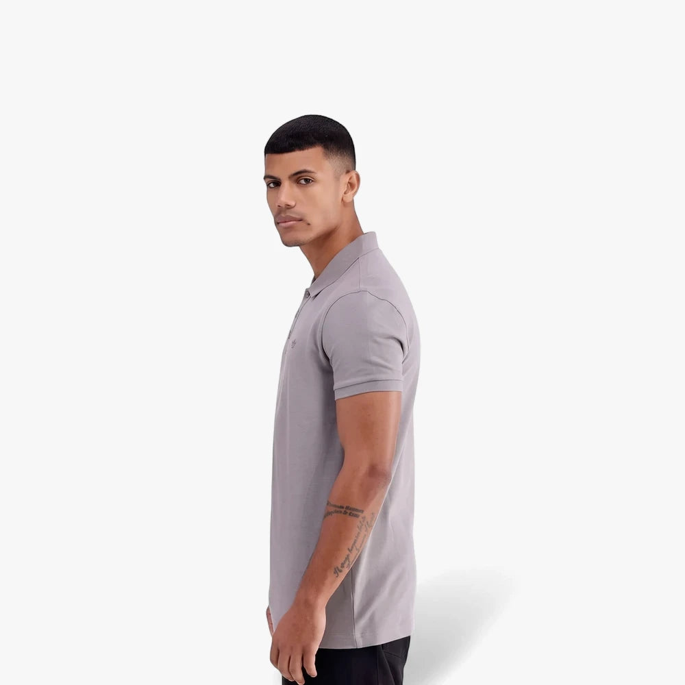 Adidas Mens Trefoil Essentials Polo Tee in grey, worn by a man in a side profile, looking towards the camera.