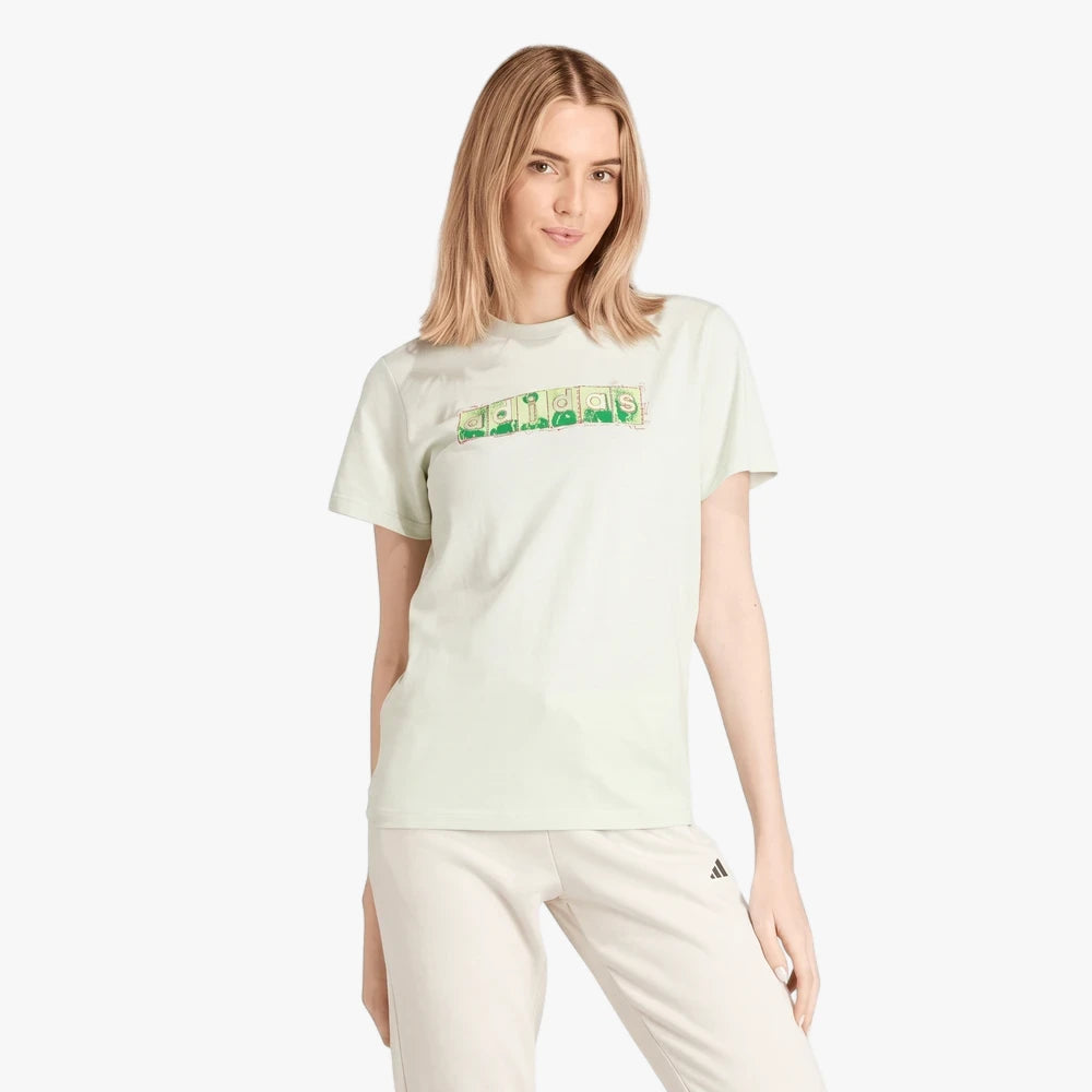 Adidas Womens Doodle Short Sleeve Tee in linen green worn by a blonde model paired with light sweatpants.