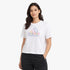 Young woman modeling a white Adidas Logo Short Sleeve Tee with a colorful outline logo, paired with black pants, smiling