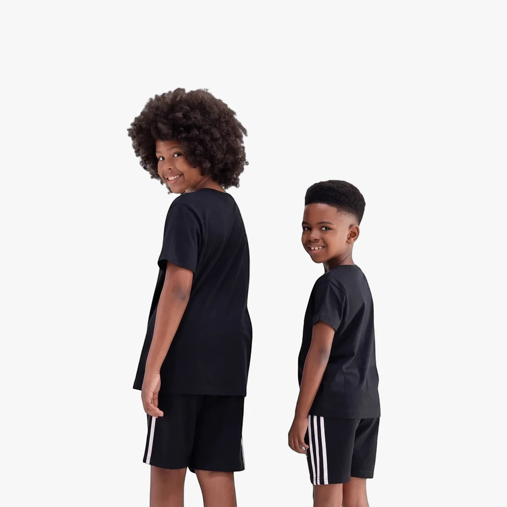Two young boys wearing black Adidas short sleeve t-shirts and black shorts with white stripes, smiling and looking back over