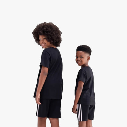 Two young boys wearing black Adidas short sleeve t-shirts and black shorts with white stripes, smiling and looking back over