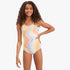 A young girl smiles wearing a vibrant Billabong Groovy Road one-piece swim suit with a multi-colored swirl pattern.