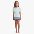 Young girl wearing a Billabong Girls Jnr Society Short Sleeve Tee in dusk blue and a denim mini skirt, full body, standing
