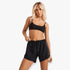 Blonde woman modeling black Billabong Fun Times boardshorts with white drawstring and matching black ribbed bikini top.