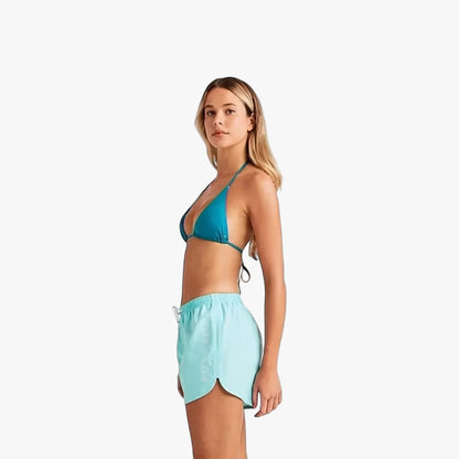 Woman wears Billabong Womens Fun Times Boardshorts High Tide in light blue and a teal bikini top, captured from a side view.
