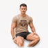 Boerboel Mens Premium Cotton Braaf Short Sleeve Tee in sand, featuring a shield logo, worn by a man in dark shorts.