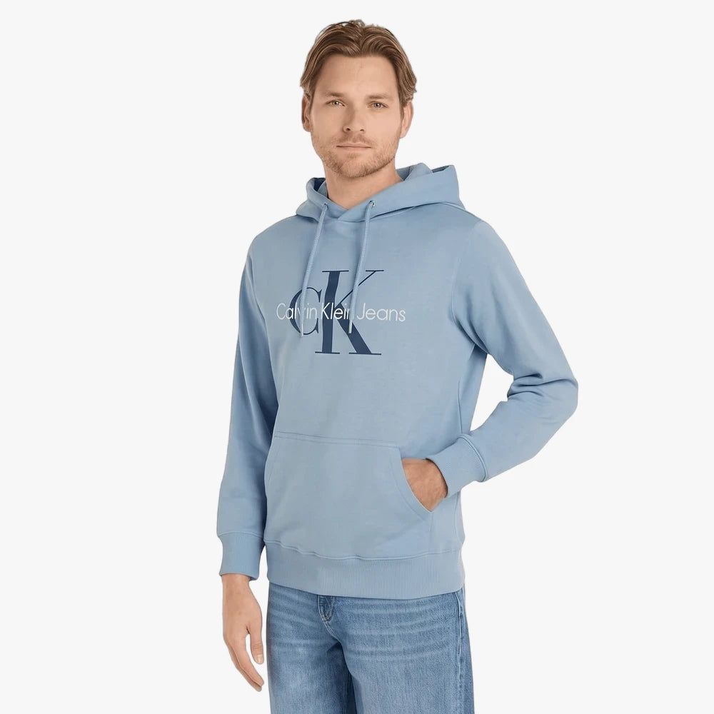 Male model in a light blue Calvin Klein Monogram Hoodie featuring a prominent &