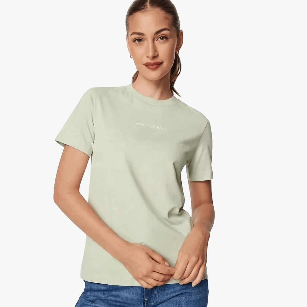 A woman models a light green Calvin Klein Institutional Straight Tee with the brand logo on the chest, paired with blue