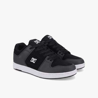 Dc Mens Manteca 4 Sneaker in black and grey with white soles, designed for skateboarding, shown from a slightly angled view.