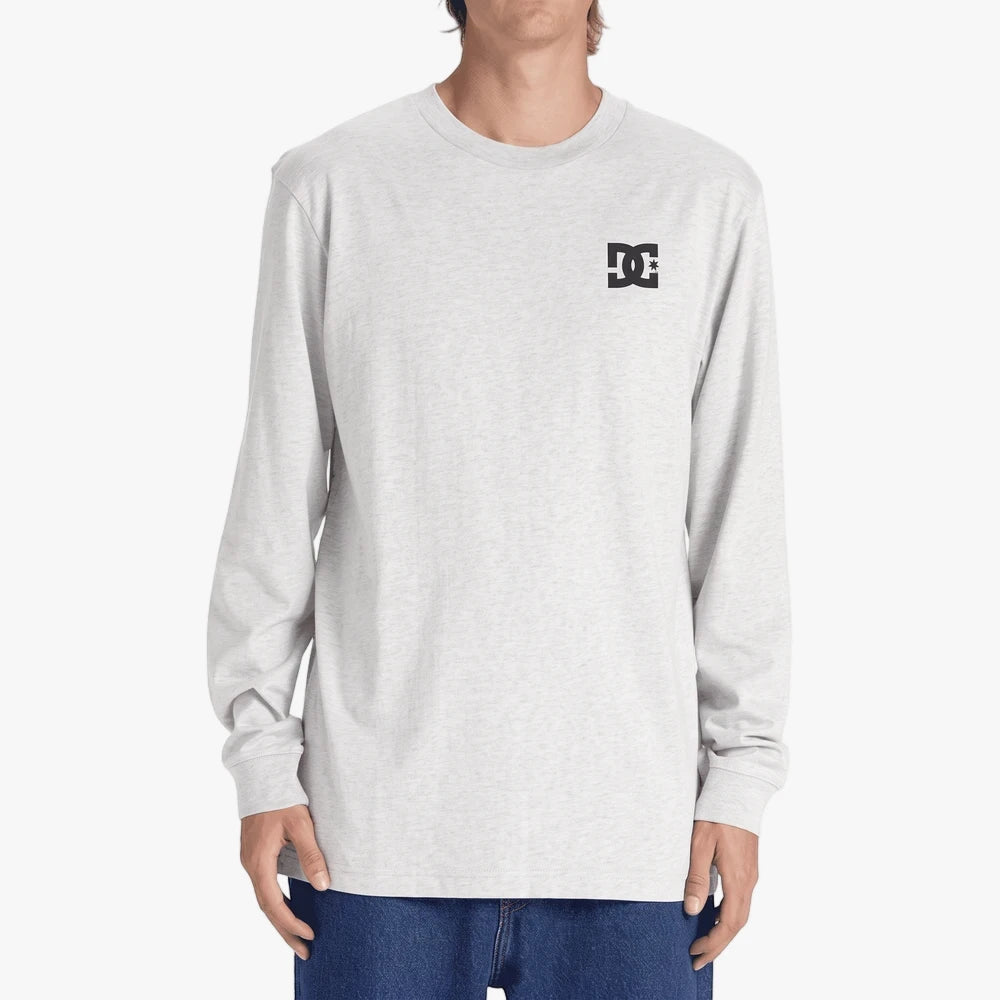 A male model wears a light grey Dc Mens Star long sleeve tee with a black DC logo on the left chest.