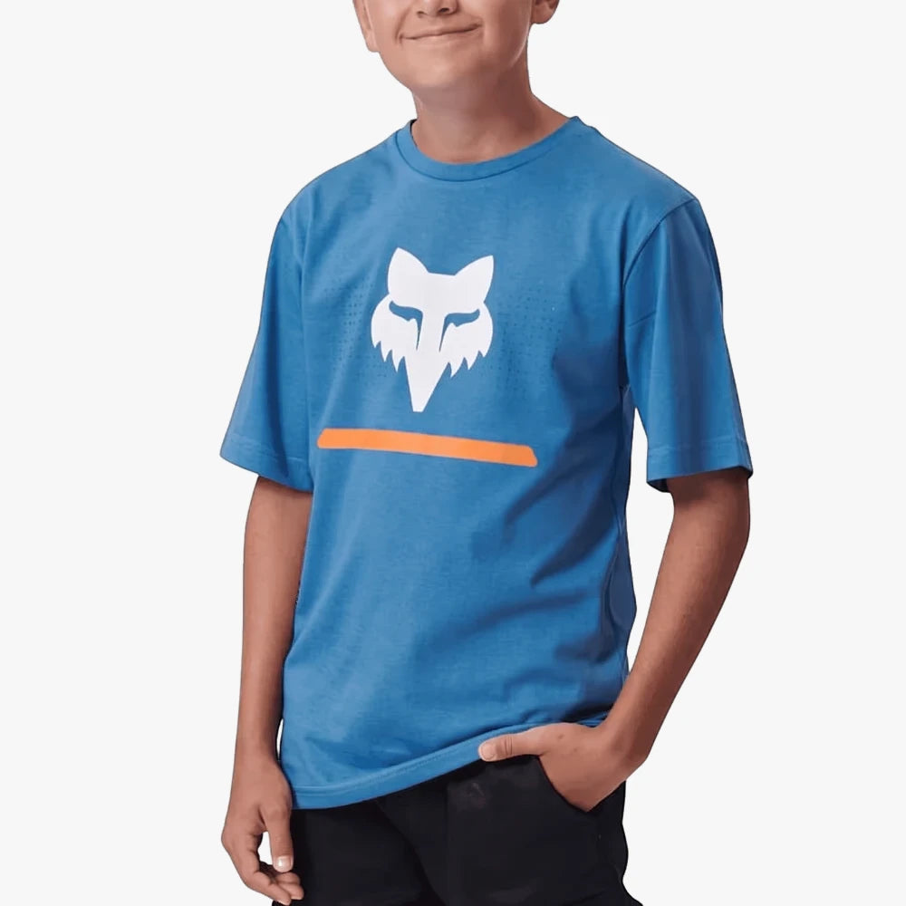 Fox Boys Optical Illusion Short Sleeve Tee in Banaff Blue, featuring a white Fox head logo and orange stripe, modeled by a