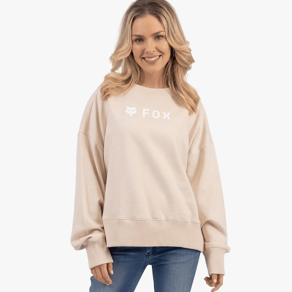 A woman models a cream Fox Mens Absolute Crew Sweater, featuring a white Fox logo on the chest. The oversized sweatshirt is