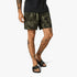 Fox Mens Essex Down N Dirty shorts in olive green tie-dye pattern, worn by a man with tattooed legs and black slide sandals.