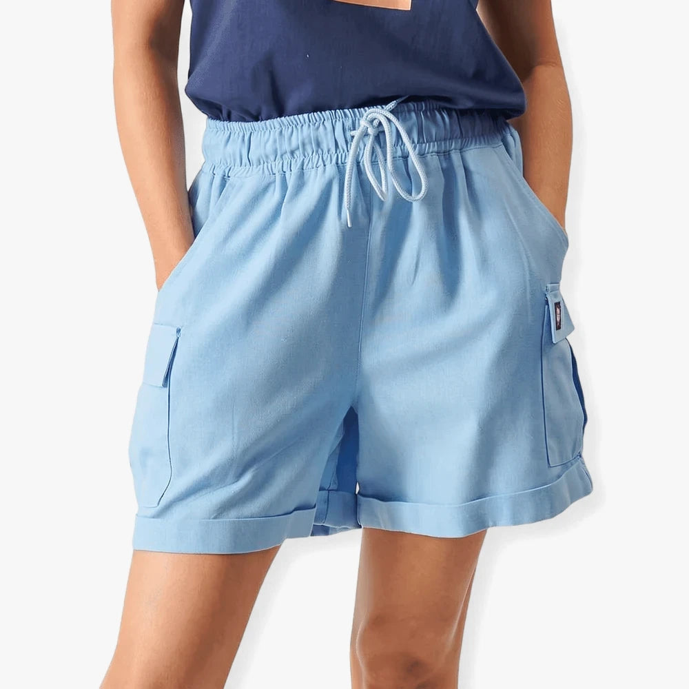 Fox Womens Flip Side Cargo Shorts in light blue, featuring an elastic waist, cargo pockets, and cuffed hems, worn by a woman.