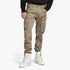 A man models G Star Mens Rovic Zip 3D Regular Tapered Cargo Pants in dune, with multiple cargo pockets, paired with white