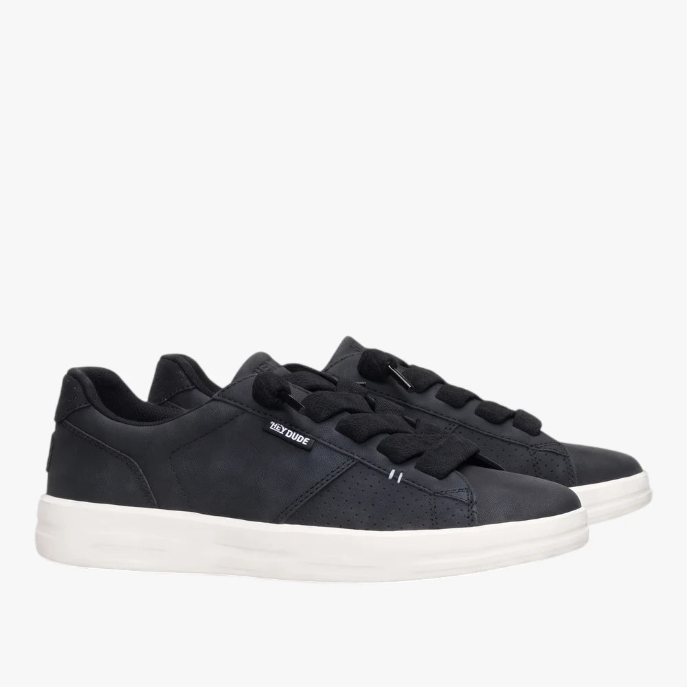 Pair of black Hey Dude Womens Karina Duo Classic Sneakers with white soles and black laces, presented in a studio setting.