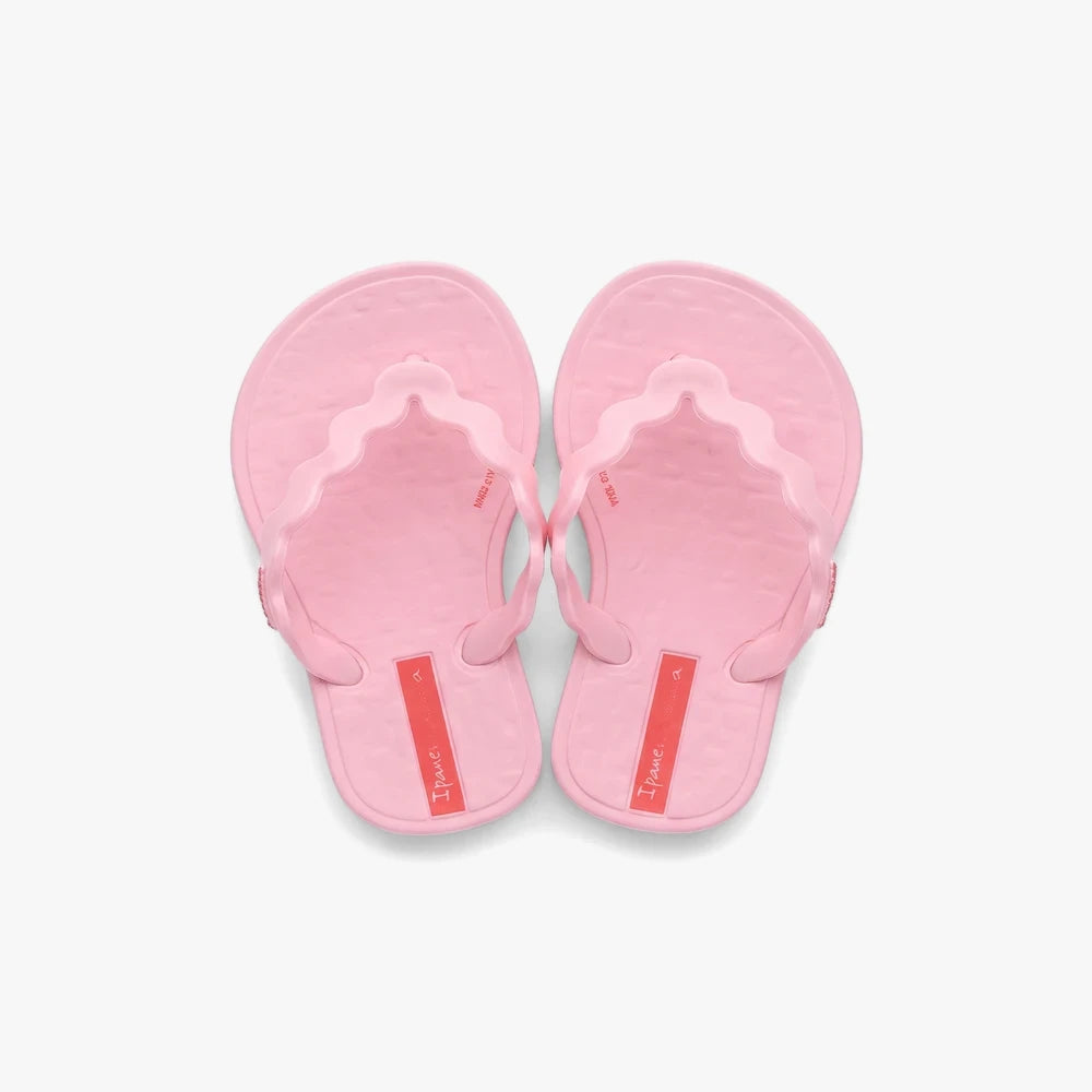 A pair of light pink Ipanema Girls Zig sandals, featuring a thong style with wavy-edged straps and small red tags on the