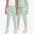 Two girls model comfortable Nike Girls Court Club Pants in sage green, featuring a white Nike logo and elastic cuffs. They