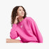 Nike Girls Long Sleeve Sweater in cerise pink, featuring a white Nike logo. A young girl with curly hair wears the crewneck