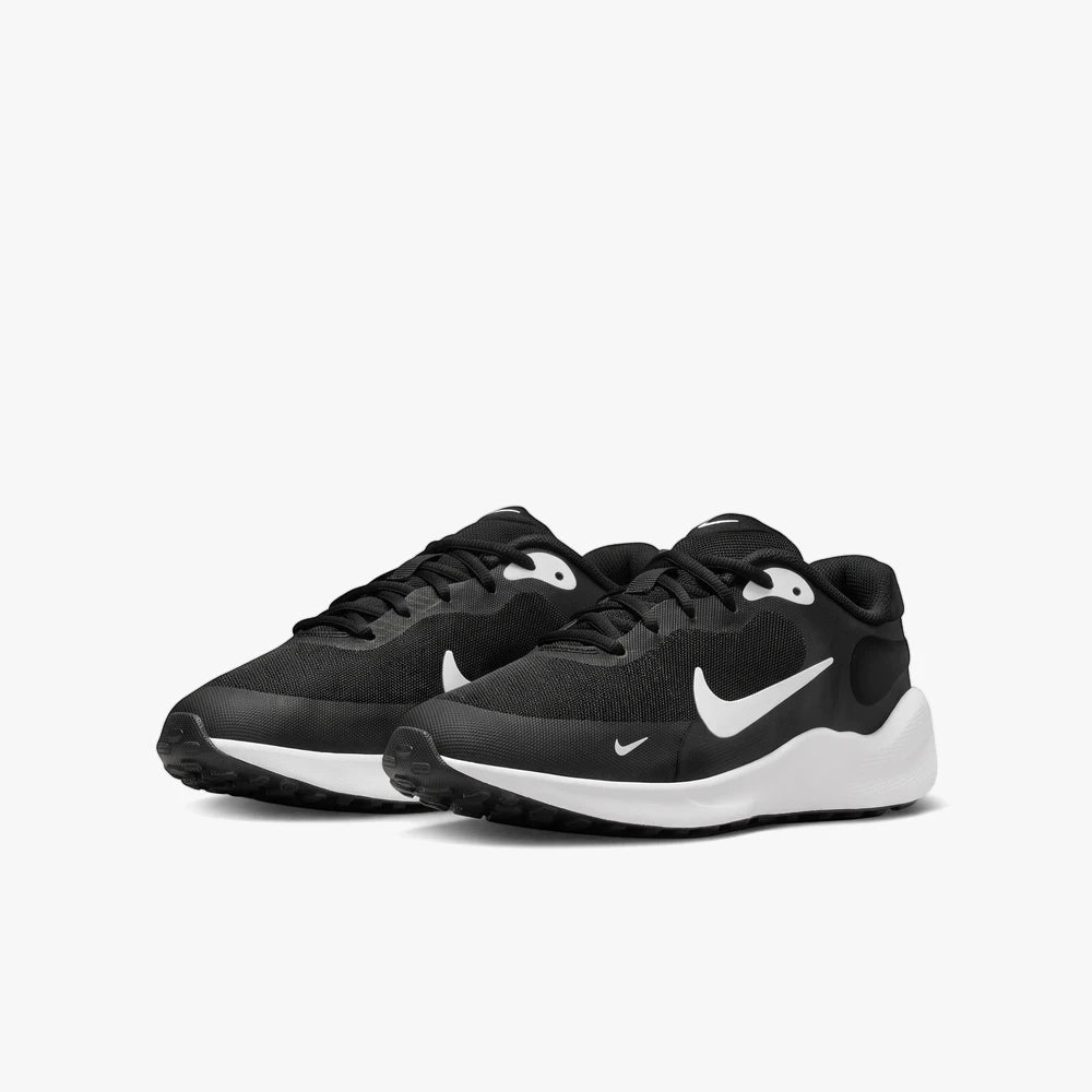 A pair of black and white Nike Girls Revolution 7 running sneakers, featuring a white swoosh and white soles, side view.