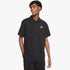 Male model wearing a black Nike short sleeve pique golfer polo shirt with a white swoosh logo and patterned pants, front