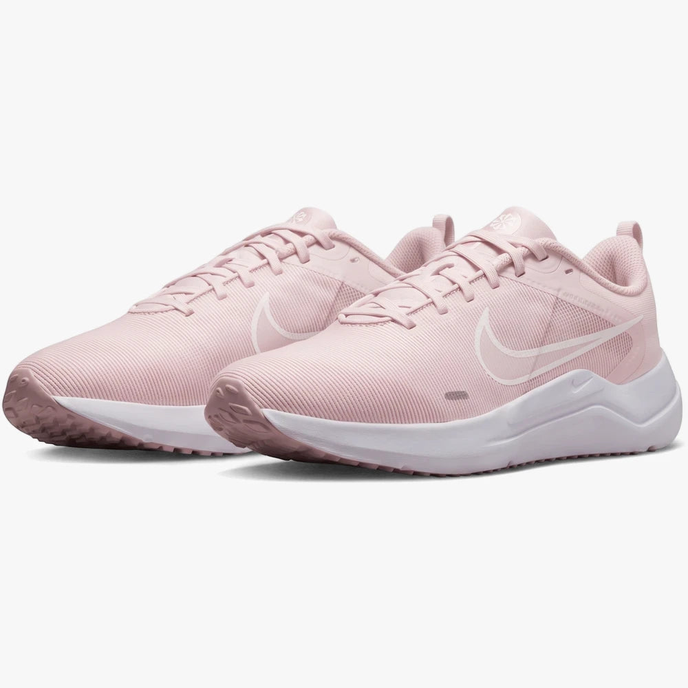 Pair of Nike Womens Downshifter 12 sneakers in white and pink, featuring a mesh upper and white sole, angled studio shot.