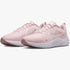 Pair of Nike Womens Downshifter 12 sneakers in white and pink, featuring a mesh upper and white sole, angled studio shot.