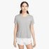 A woman models a grey Nike Miler Running Short Sleeve Tee and white shorts, standing confidently with a neutral expression.