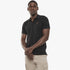 Black man models a black Pierre Cardin short sleeve polo shirt with khaki cargo pants, standing against a white background.