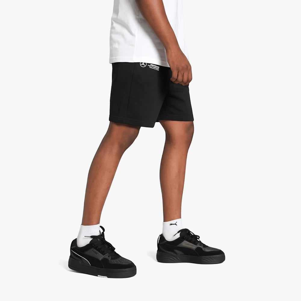 Mens black Puma MAPF1 Ess shorts paired with a white t-shirt and black sneakers, captured in a dynamic side profile.