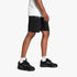 Mens black Puma MAPF1 Ess shorts paired with a white t-shirt and black sneakers, captured in a dynamic side profile.